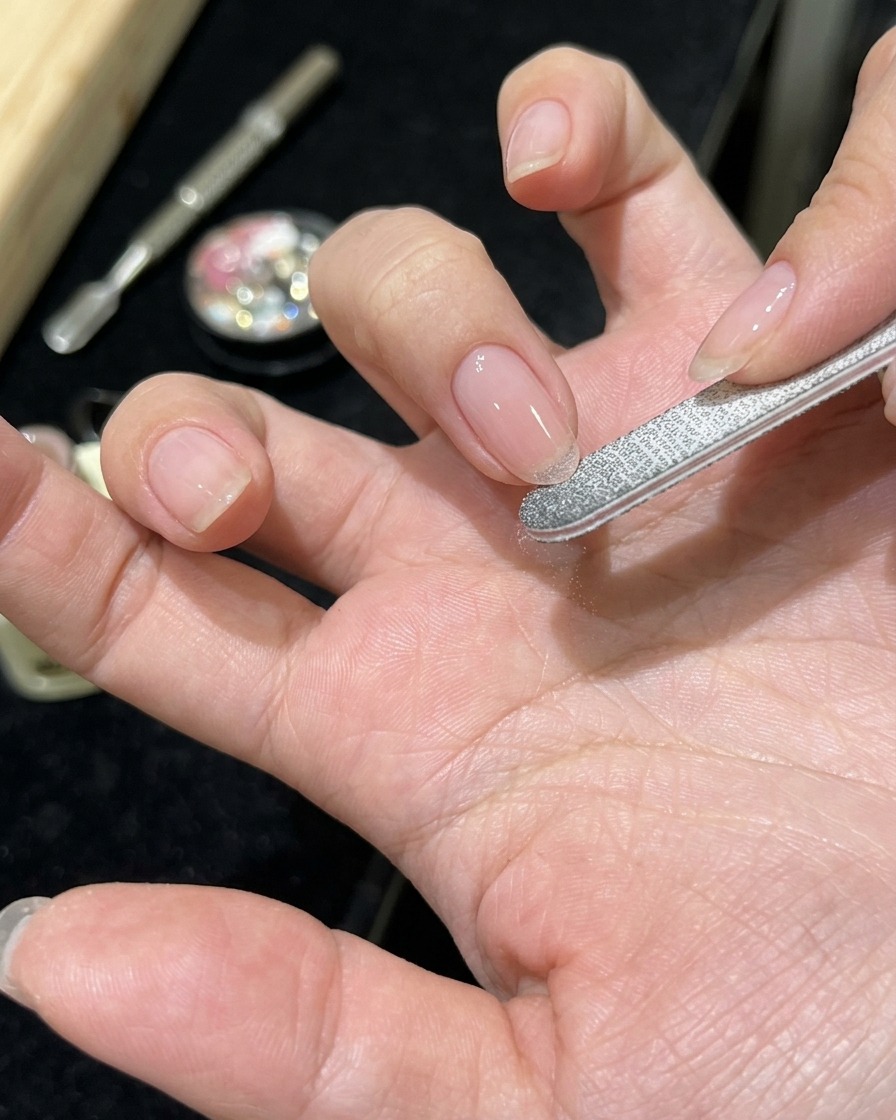 Gros plan dune main avec lapplication dun gel rose diaphane sur un ongle naturel propre.