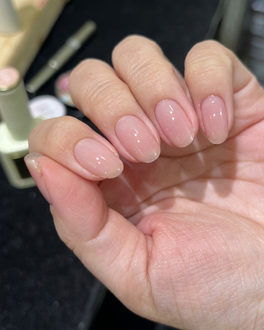 Une main positionnée sous une lampe LED professionnelle pour ongles.