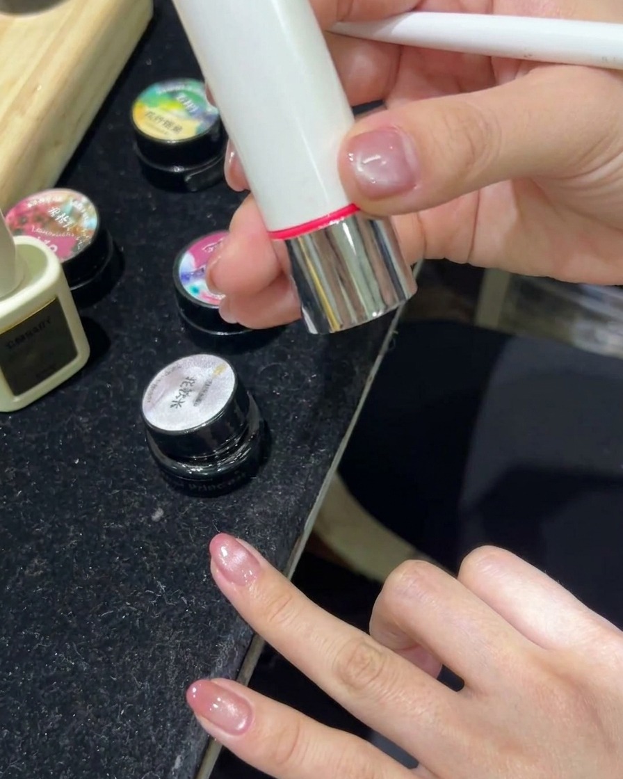 Une main reposant à lintérieur dune lampe LED avec la lumière allumée, catalysant les ongles en gel cat-eye.
