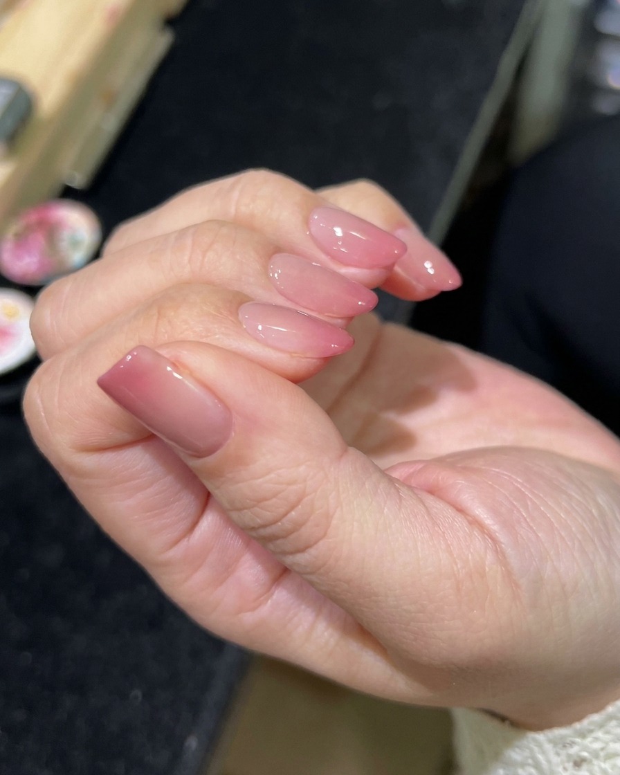 Un pinceau appliquant un top coat transparent brillant sur le nail art magnétique terminé.