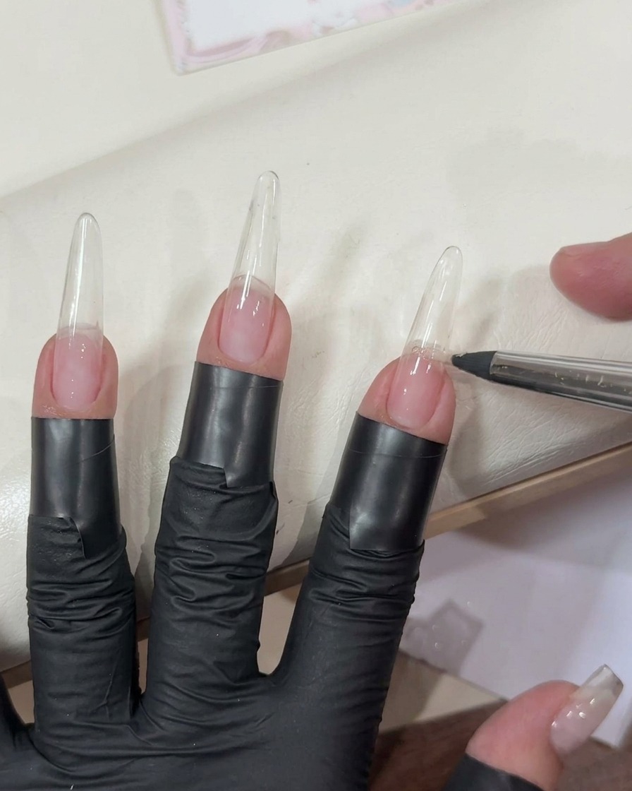 Application dun gel rose clair transparent sur une extension dongle longue et transparente avec un pinceau plat.