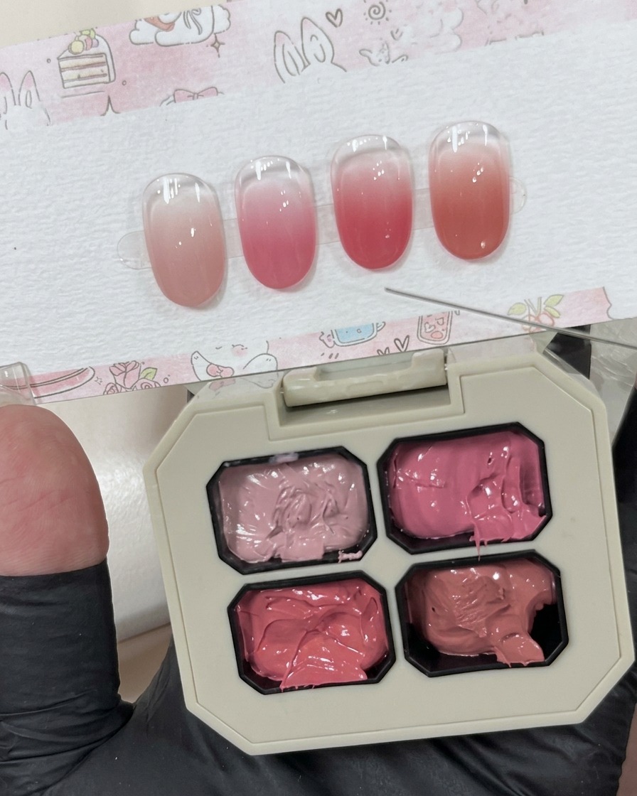 Une petite quantité de gel rose crémeux déposée sur une surface blanche à côté de la palette principale.