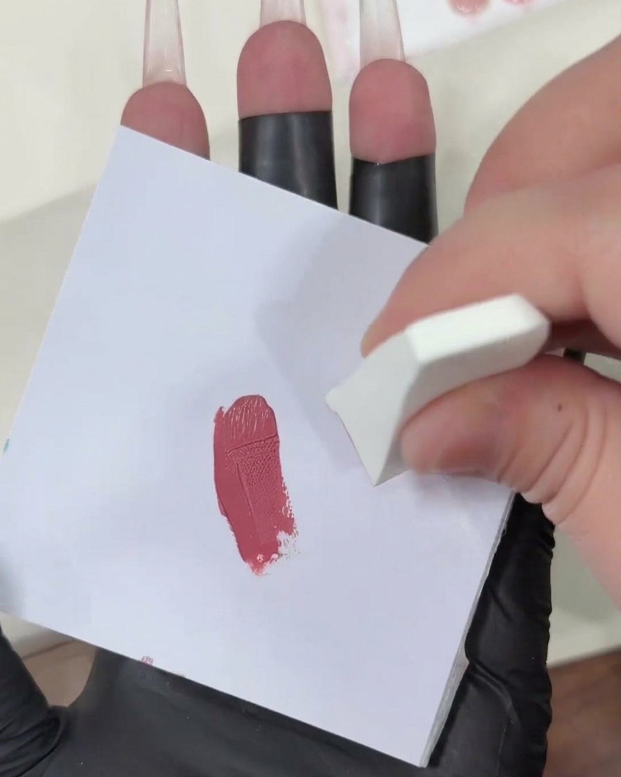 Tapoter une éponge de maquillage chargée de gel sur une surface blanche propre pour diffuser la couleur rose.