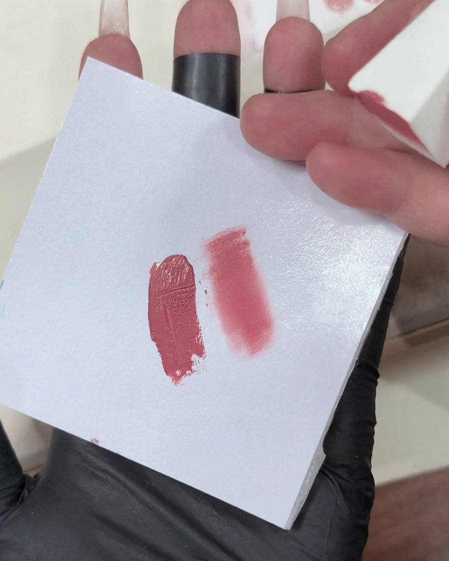 Une éponge de maquillage avec un dégradé de gel rose clair en cours dapplication sur le bout dun ongle.
