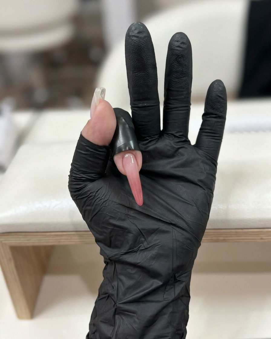 Un ongle avec un bijou posé reposant sous une lampe de catalyse LED professionnelle.