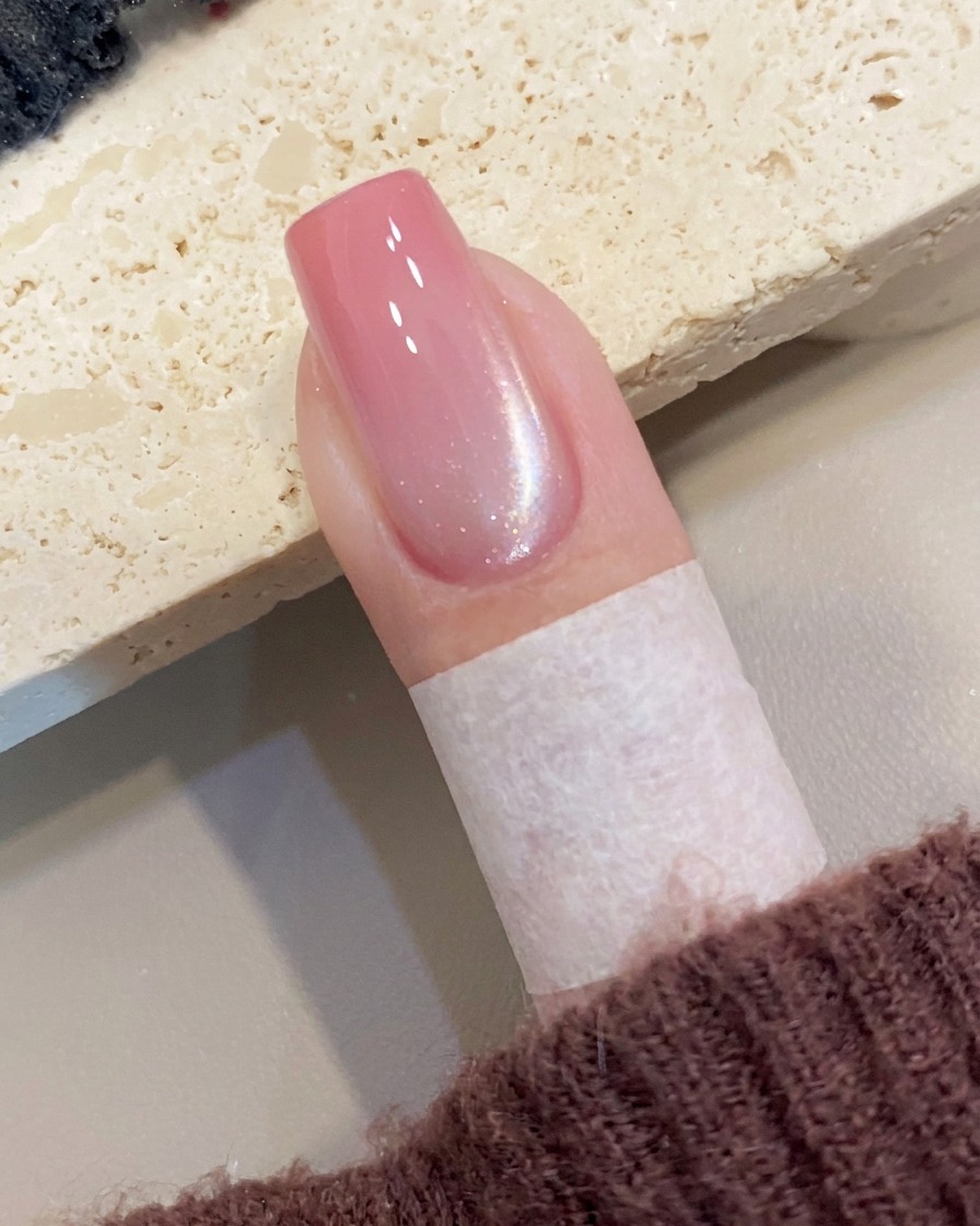 Un outil magnétique maintenu près du côté de longle, créant une ligne de scintillement diagonale dans le gel œil de chat humide.