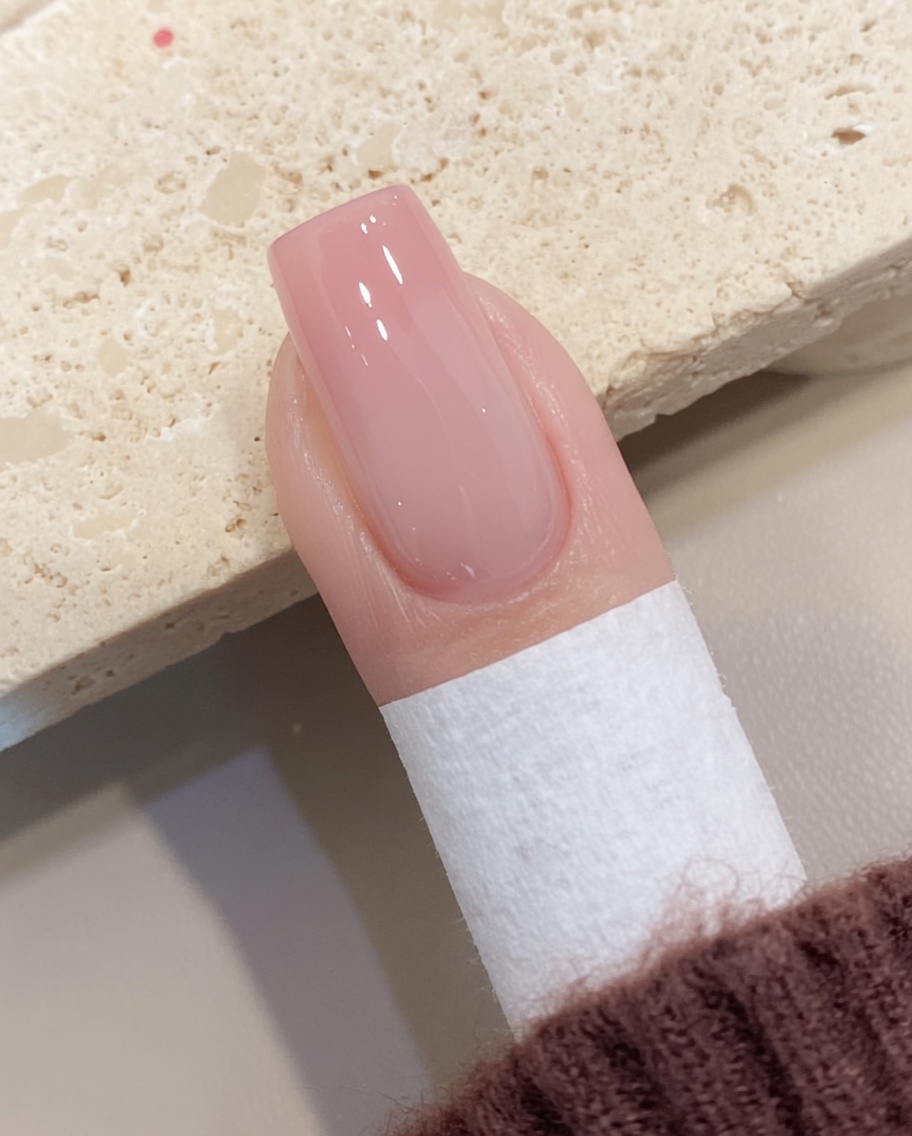 Une lingette non pelucheuse retirant le résidu collant de la surface dun ongle en gel catalysé.