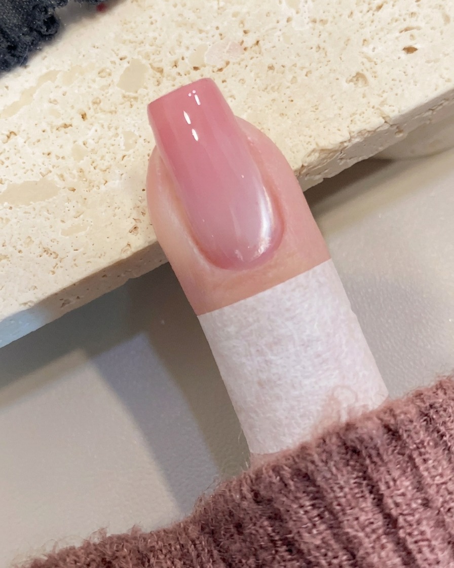 Une petite quantité de gel couleur pêche déposée au bord libre de longle avec un pinceau.