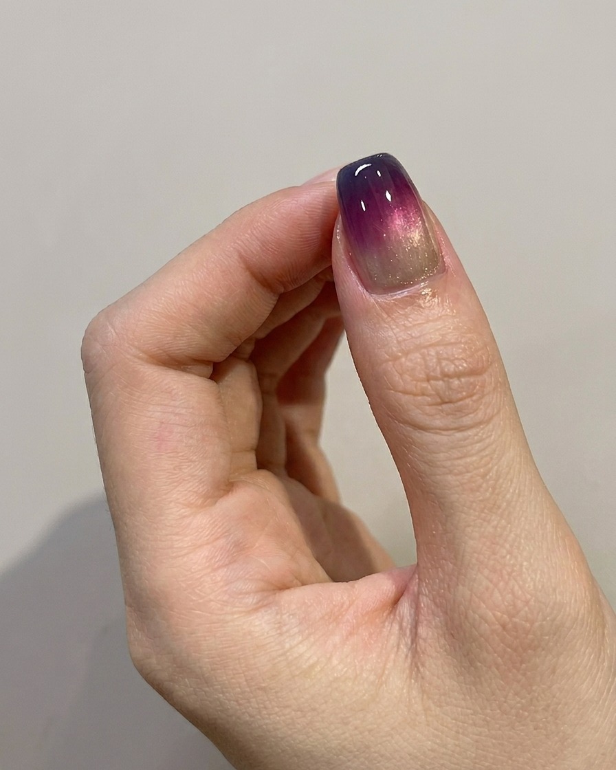 Un pinceau appliquant une couche de finition brillante sur un design dongles ombré bleu-violet terminé.