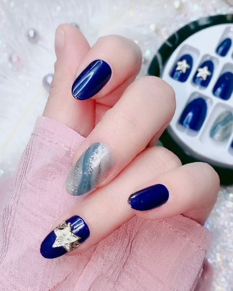 Gros plan dun doigt décollant un petit film plastique transparent au dos dun faux ongle bleu électrique.