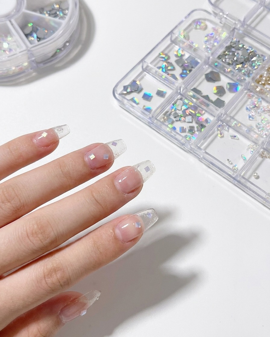 Un stylo dotting plaçant des éclats de coquillage irisés sur du gel humide.