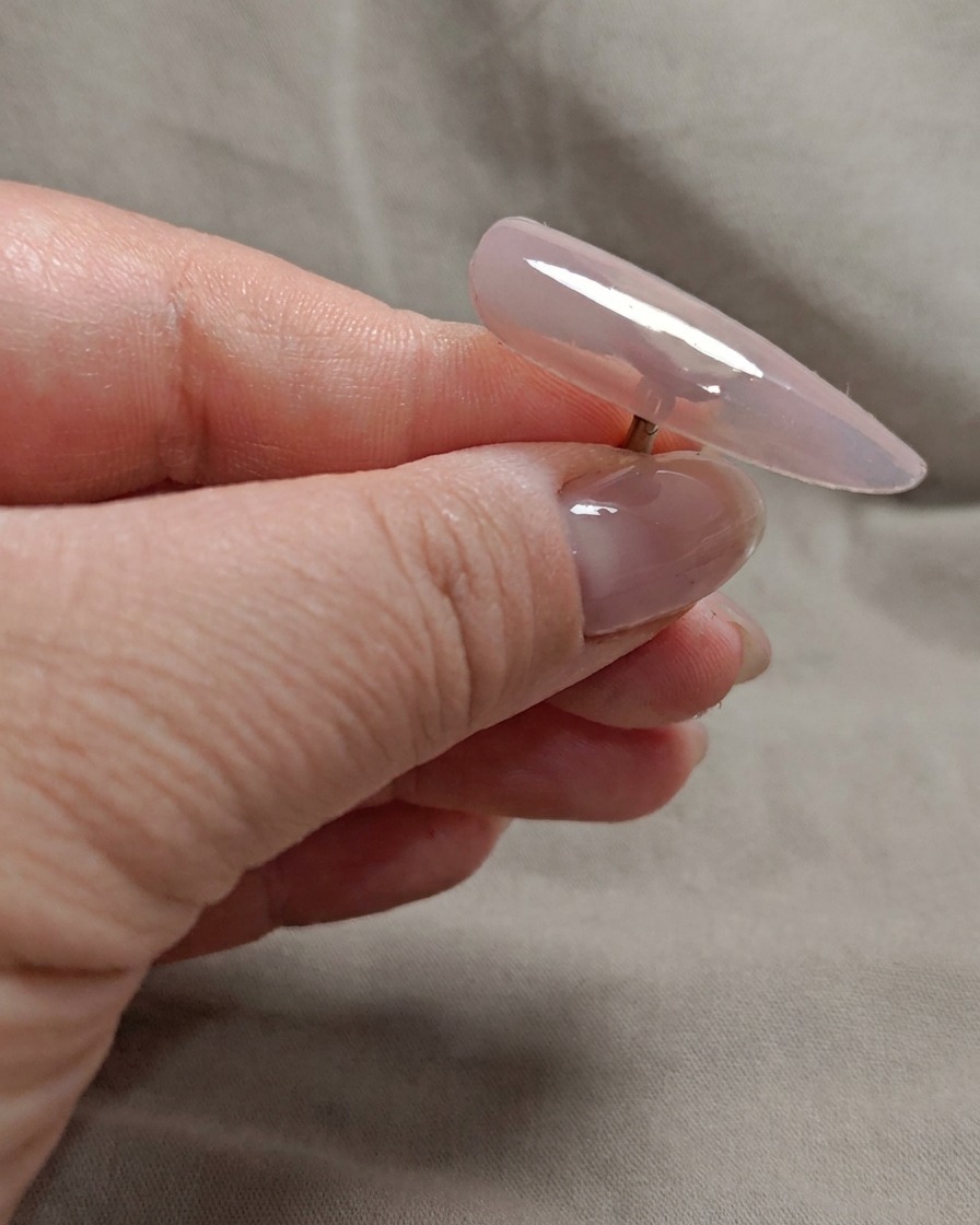Un pinceau appliquant une deuxième couche de gel rose nude transparent sur la pointe de longle.