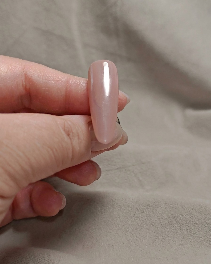 Une éponge à maquillage tamponnant du gel blanc laiteux sur la pointe dun ongle rose.