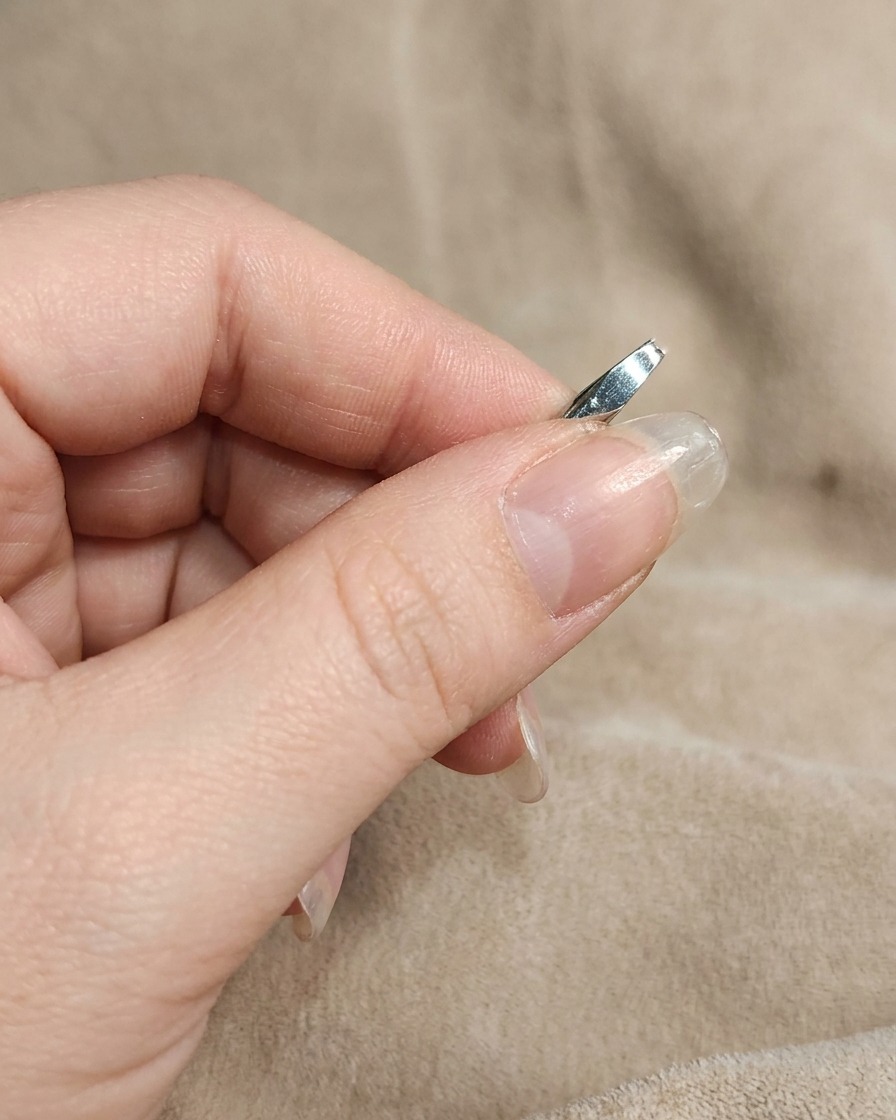 Gros plan dun ongle manucuré frotté avec de la poudre chrome blanche à laide dun doigt.