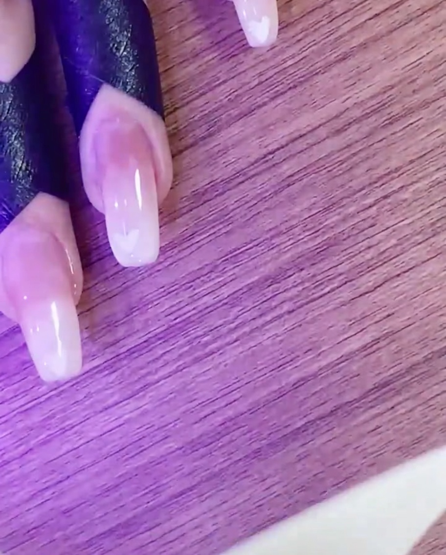 Une main catalysant le design de nail art cœur sous une lampe UV/LED.