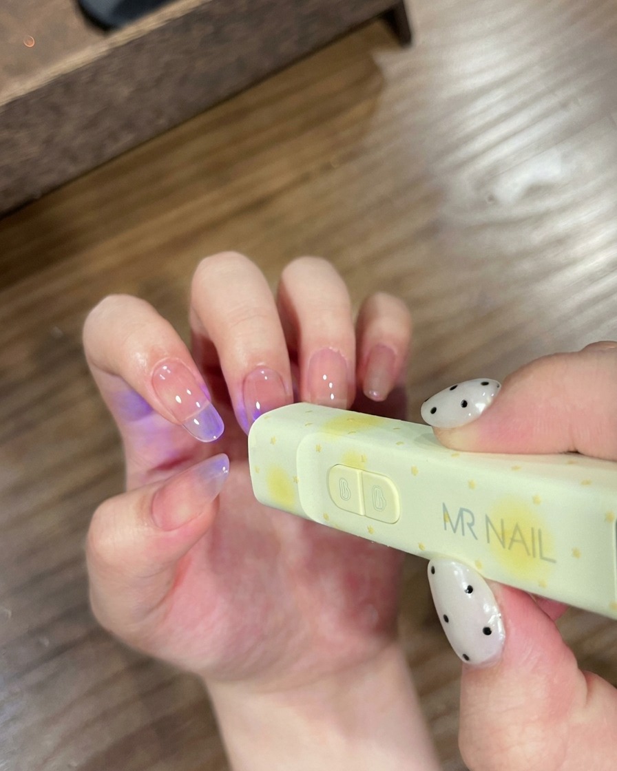 Ongles positionnés sous une petite lampe UV de marque MR NAIL pour catalyser.