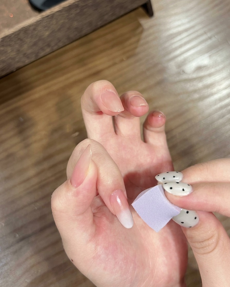 Une main avec des ongles ombrés placée sous une lampe UV/LED pour catalyser le dégradé.