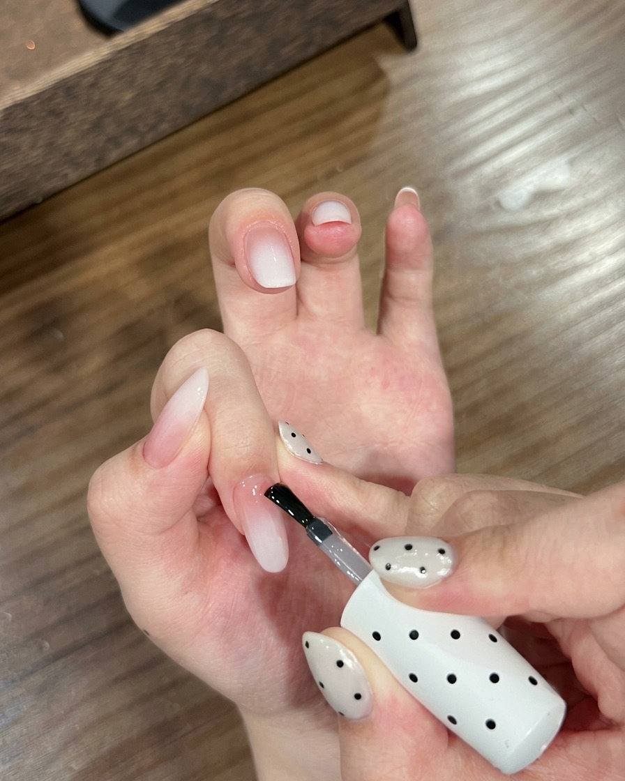 Gros plan dune main avec des ongles dégradés positionnée dans une lampe à ongles UV.