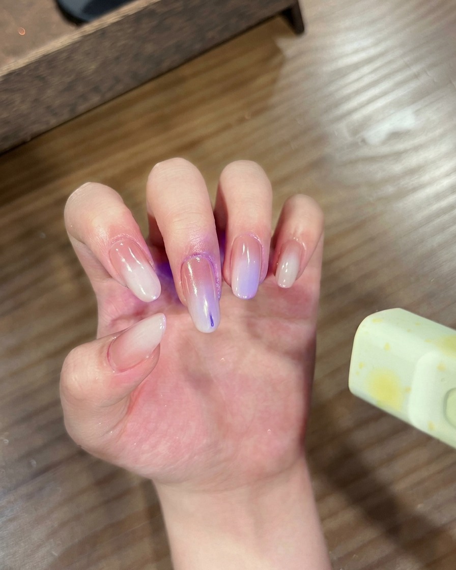 Une main avec des ongles dégradés chrome placés dans une lampe UV/LED pour la catalyse.