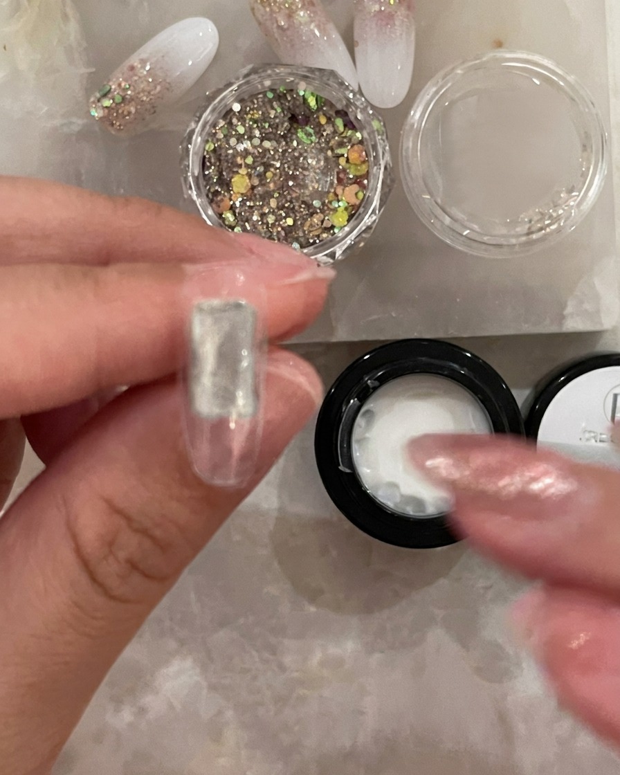Un petit pinceau applique une fine couche de base transparente au centre dune capsule à ongle.