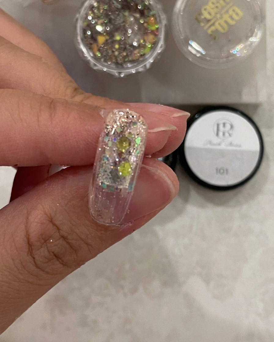 Gros plan dune capsule sous la lampe, montrant le gel de structure durci sur les paillettes.