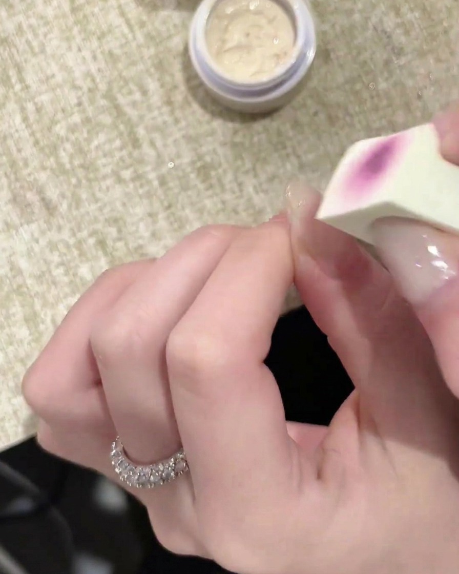 Gros plan dun embout mousse appliquant une couche de gel blanc sur un ongle.