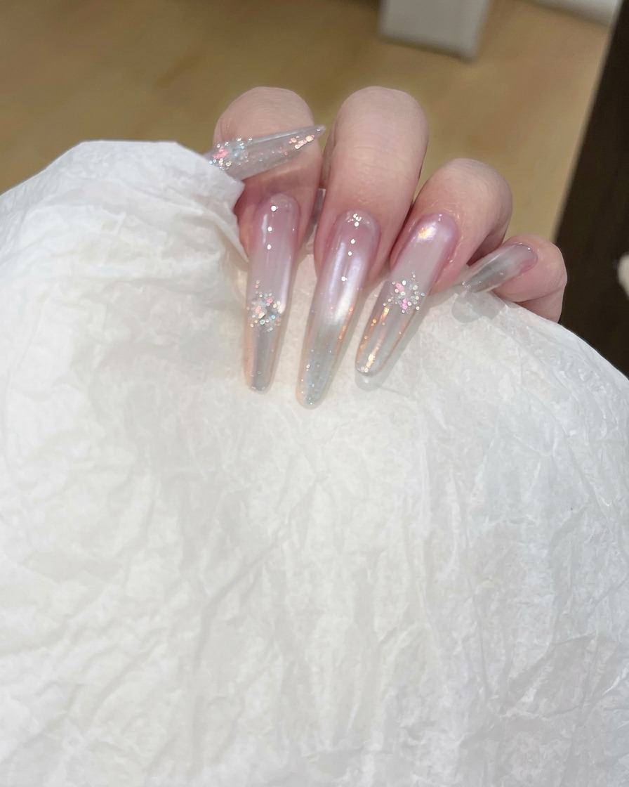 Main utilisant un coton pour nettoyer la surface dun ongle long transparent.