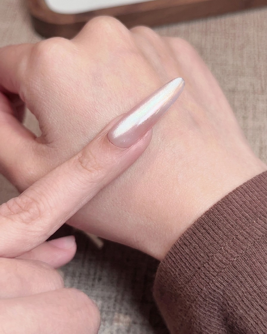 Un pinceau à ongles appliquant un top coat rose transparent sur un ongle avec un dégradé blush, avant la catalyse finale.