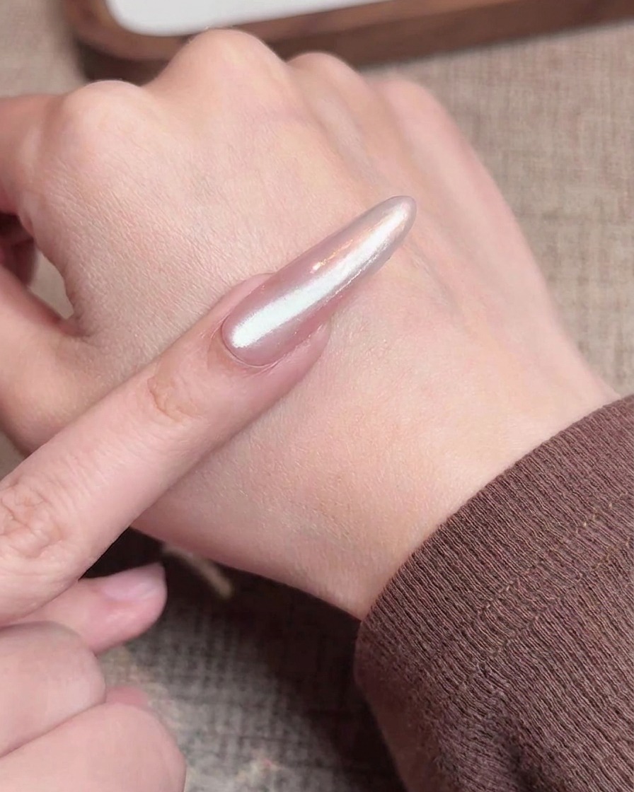Un pinceau appliquant une couche de gel cat eye scintillant sur un ongle avec un dégradé chrome.