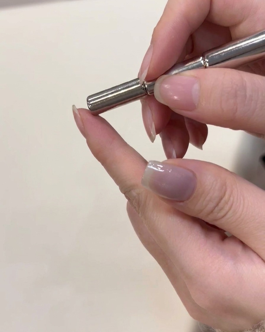 Un aimant placé juste au-dessus dun ongle recouvert de gel magnétique humide pour façonner les particules.