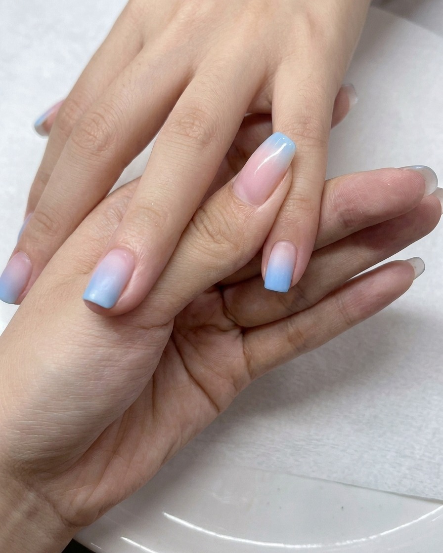 Un pinceau appliquant une couche de top coat transparent sur les ongles en dégradé.