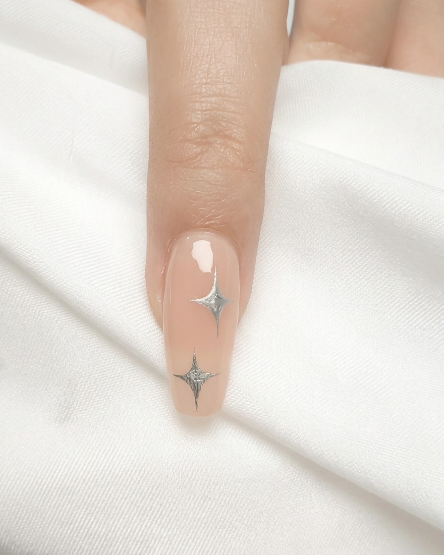 Un pinceau à ongles appliquant une fine couche de vernis gel nude sur un ongle naturel.