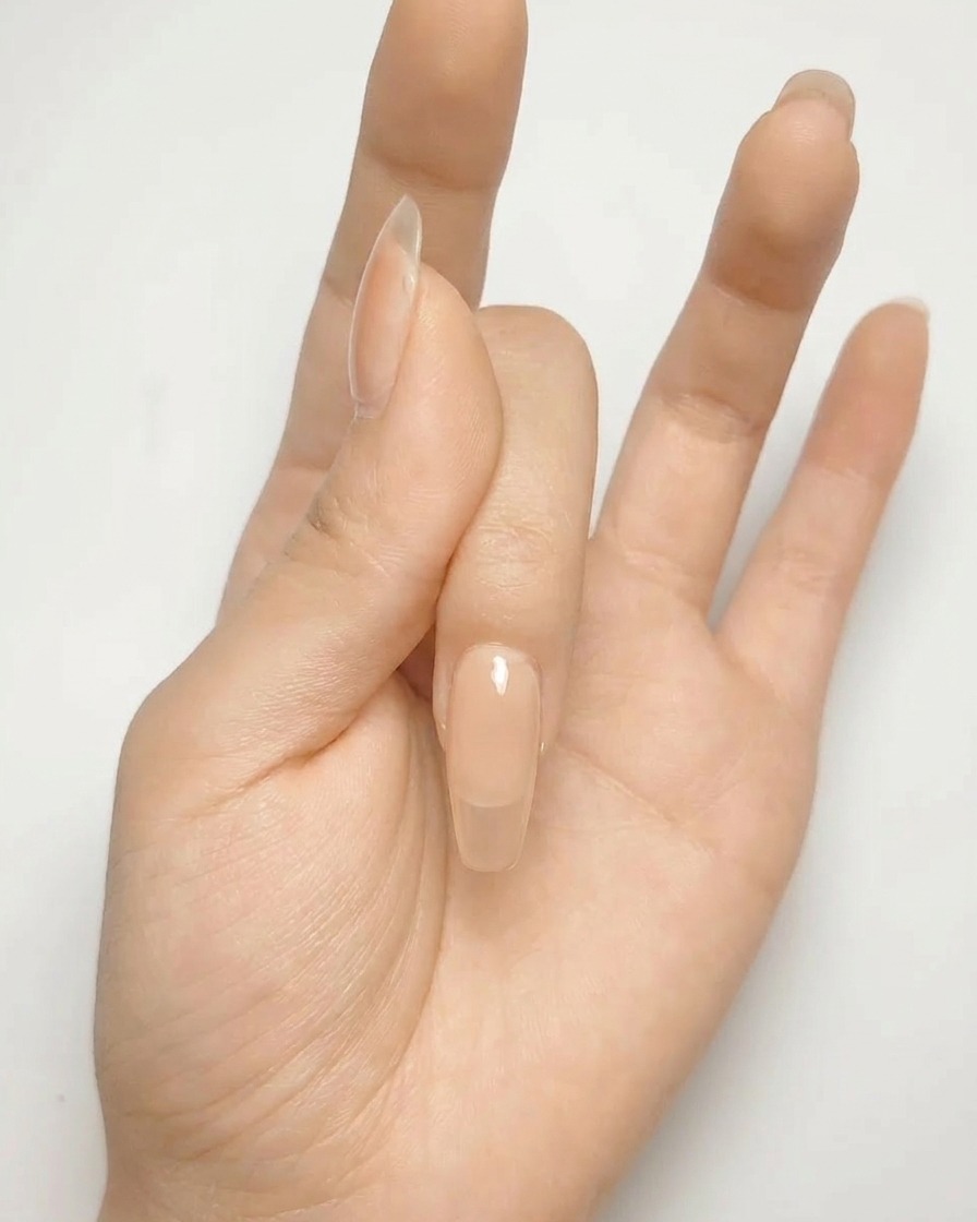 Gros plan dun ongle en gel nude avec une forme de croix argentée peinte sur la surface.