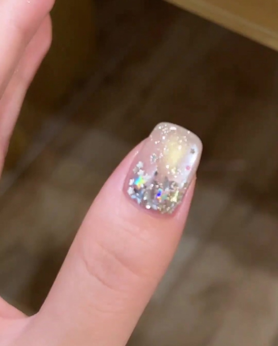 Un ongle avec un mélange de paillettes étoiles grandes et petites disposées sur la plaque de longle.