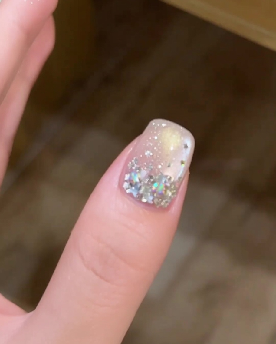 Une main positionnée dans une lampe à ongles professionnelle, avec longle décoré clairement visible sous la lumière UV.