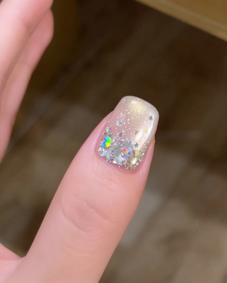 Gros plan dune main avec des ongles décorés détoiles reposant dans une lampe UV pour la catalyse.