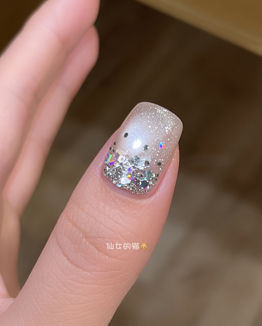 Un pinceau appliquant une couche finale de top coat transparent brillant sur un ongle décoré détoiles.
