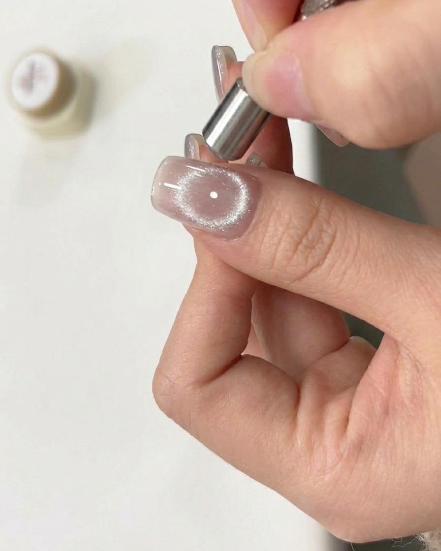 Un aimant déplacé en mouvement circulaire au-dessus dun ongle verni encore humide pour créer un effet danneau.