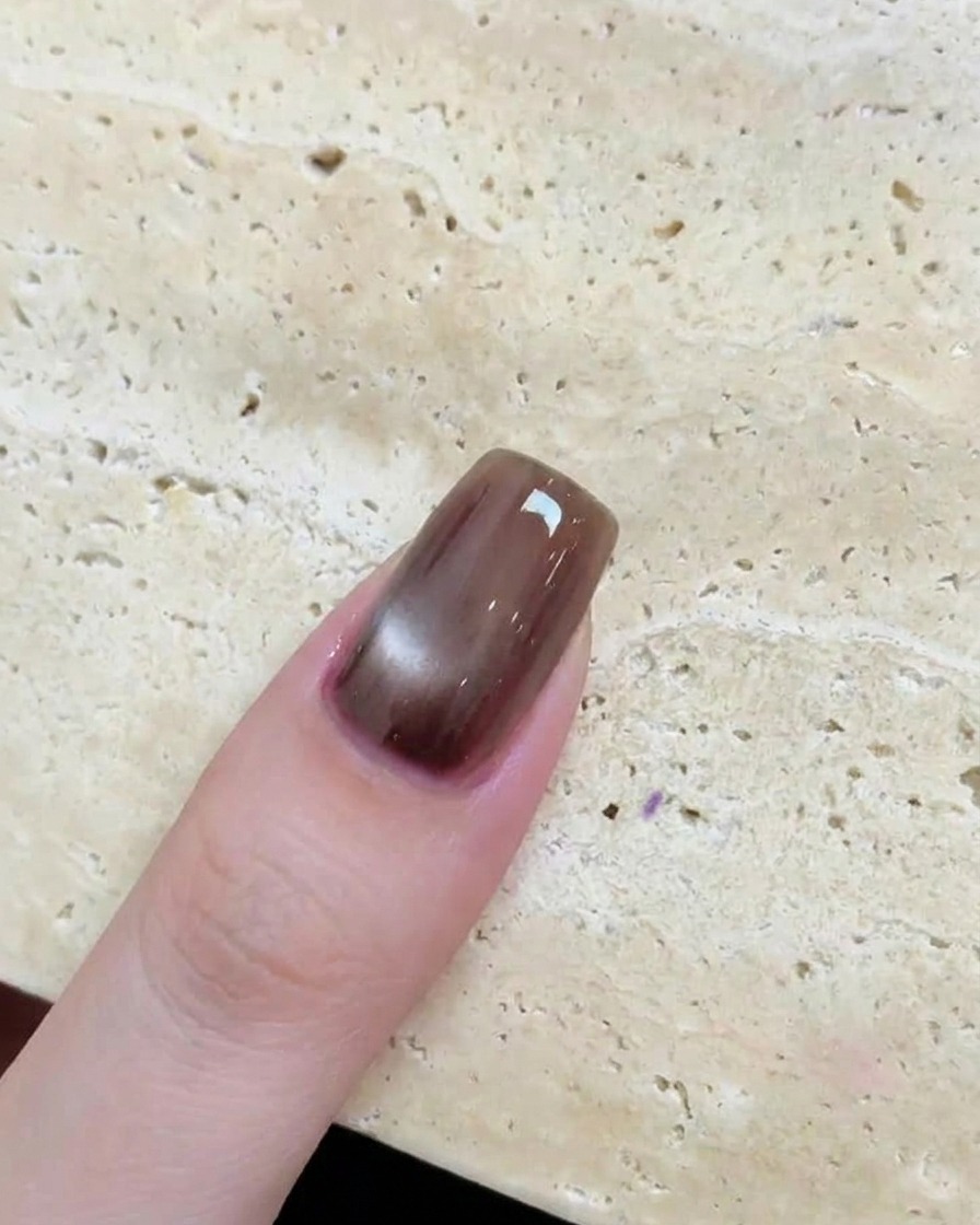 Gros plan dun ongle marron brillant avec un effet œil de chat circulaire et réfléchissant après catalysation.