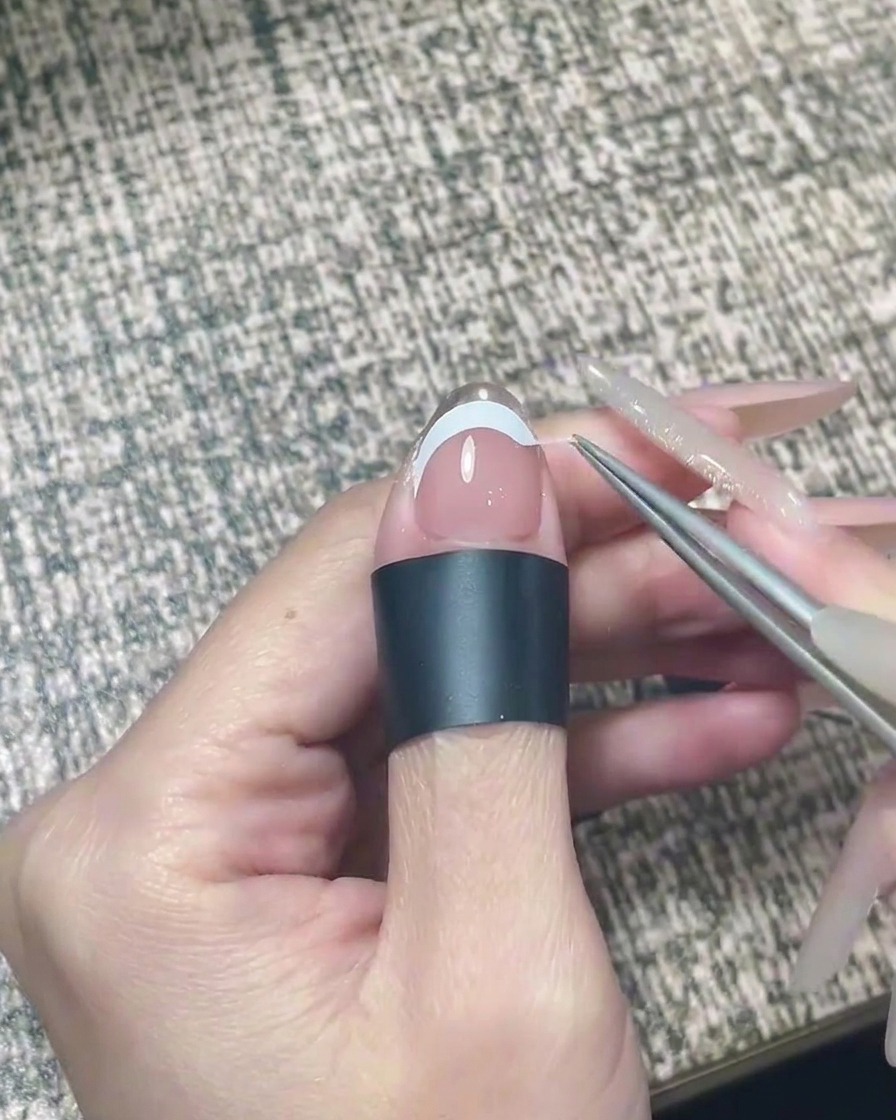 Une lime à ongles polissant doucement le bord libre dun ongle avec du chrome argenté appliqué.
