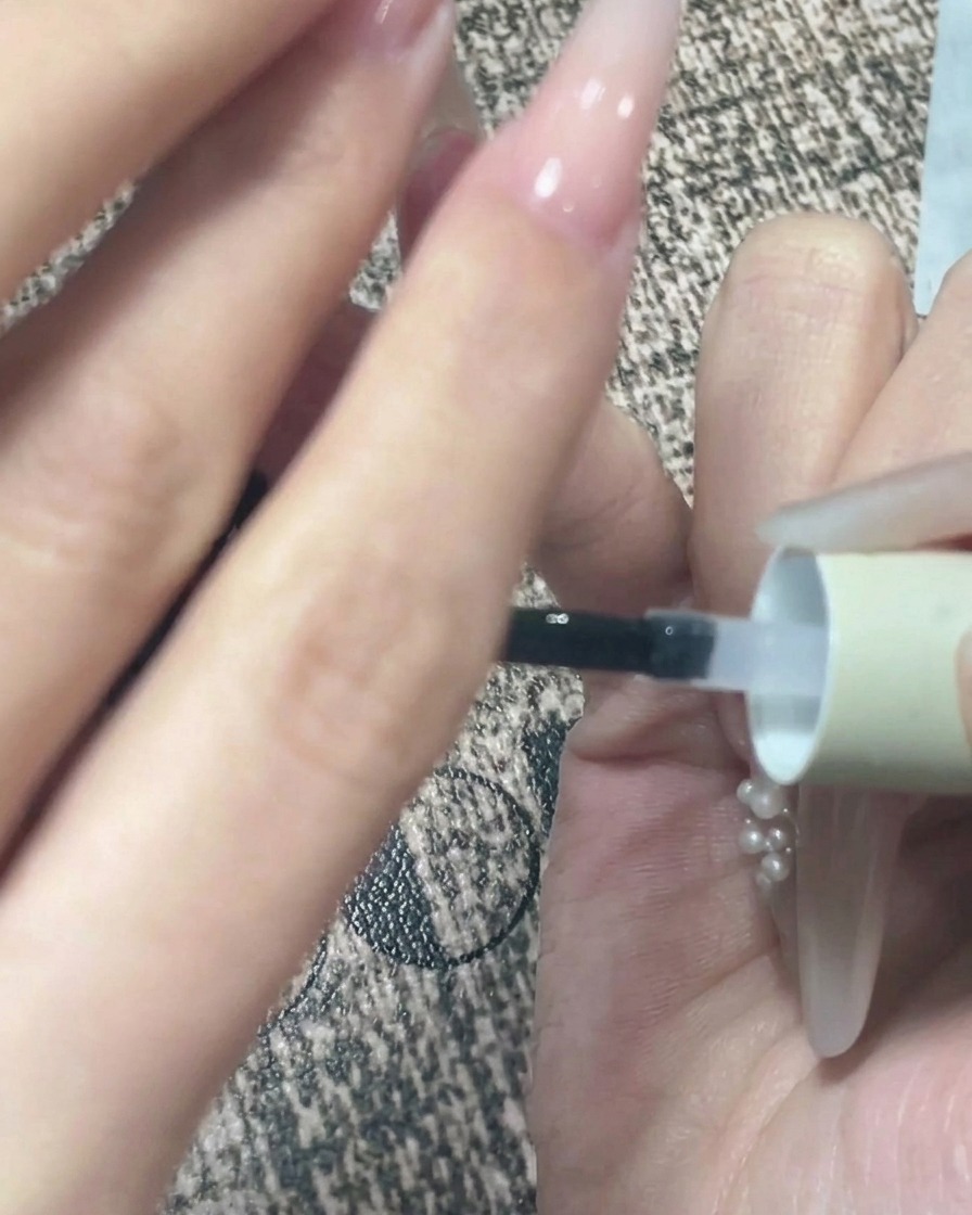 Gros plan dune main tenue à lenvers après lapplication du top coat pour permettre au gel de sauto-niveler.