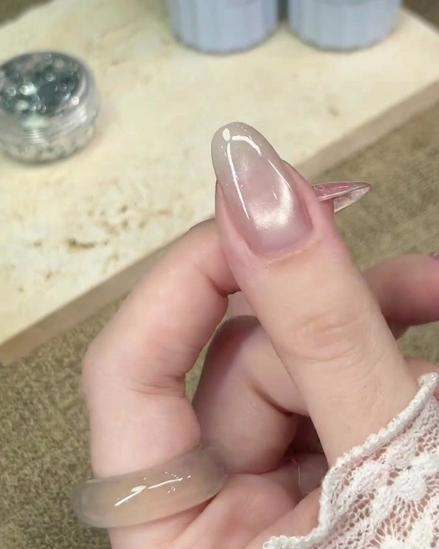 Gros plan sur un ongle en vernis semi-permanent œil-de-chat catalysé, montrant une texture de surface lisse et finie.