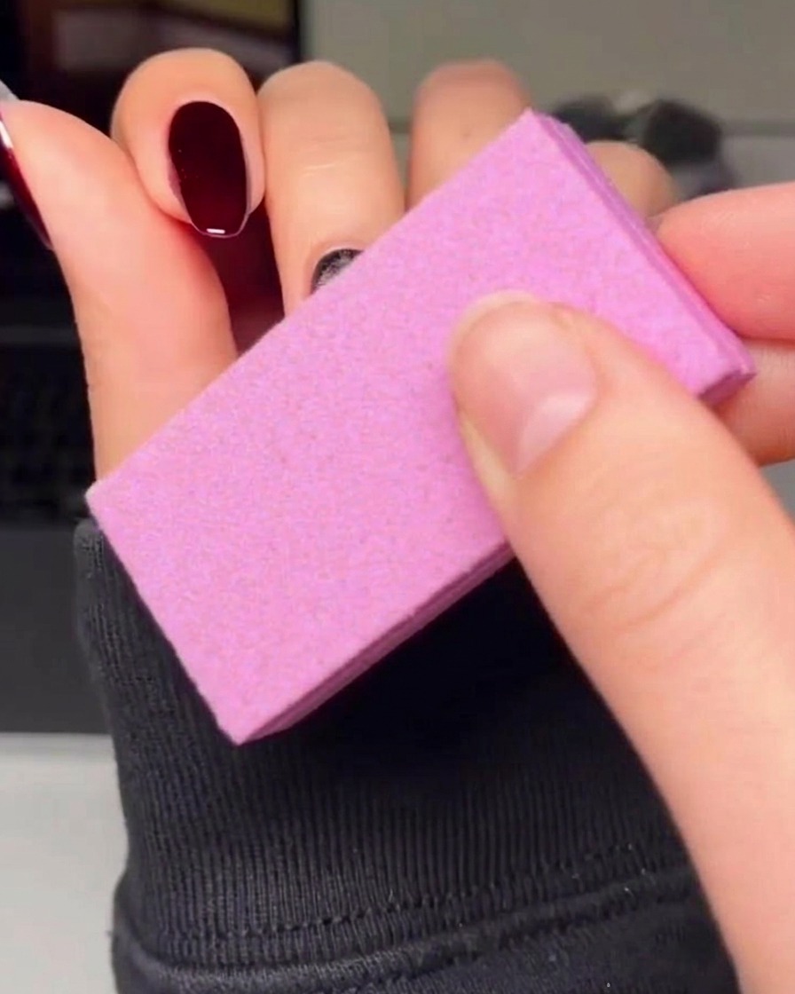 Un pinceau liner fin traçant soigneusement le contour dun cœur rouge sur un ongle avec du vernis gel noir.