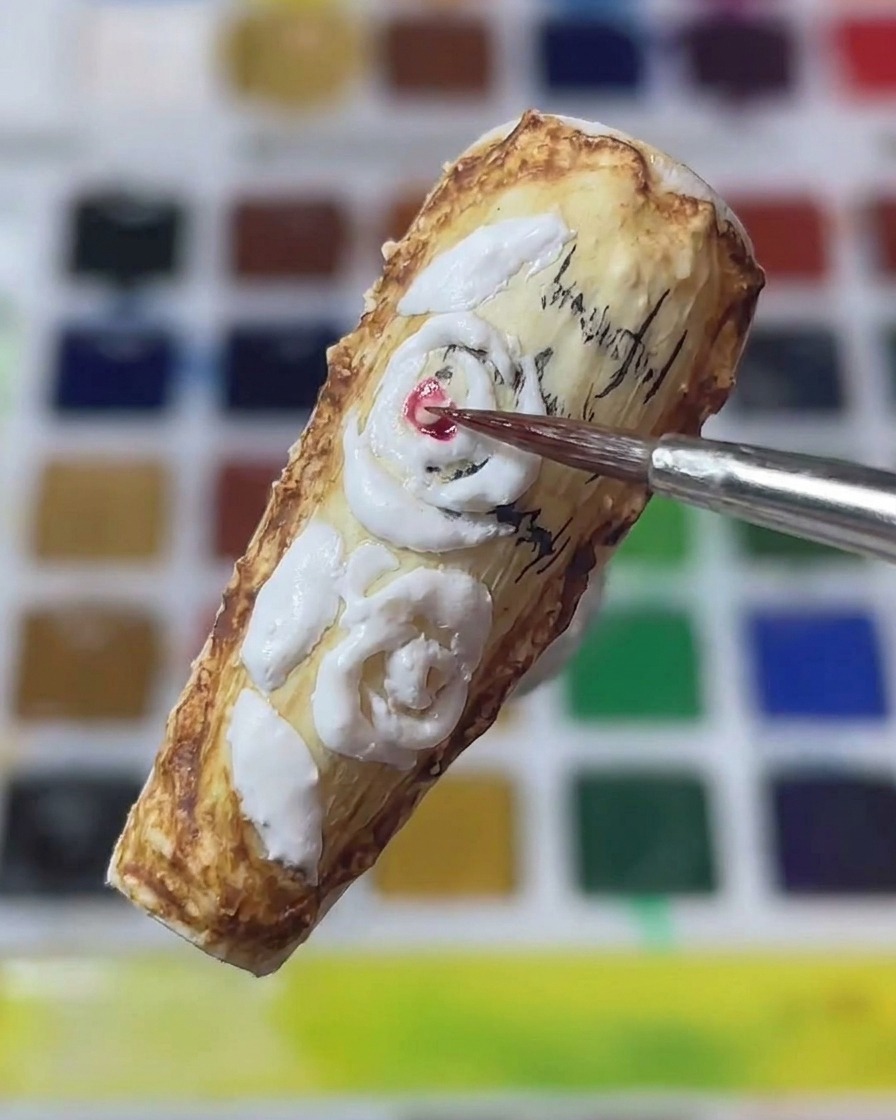 Gros plan dun pinceau fin appliquant du pigment rouge au centre de roses 3D sculptées sur un ongle style vintage.