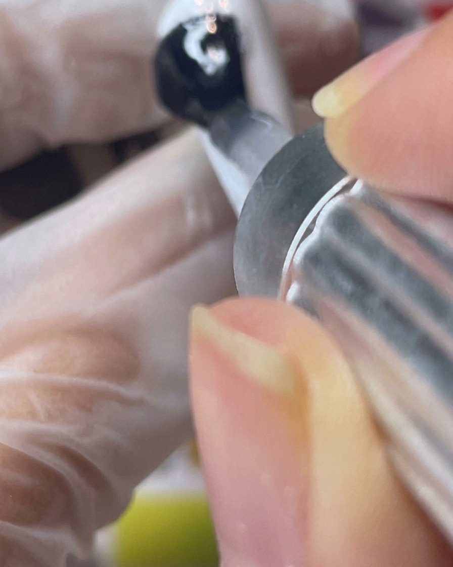 Application dun top coat mat transparent sur une capsule peinte en blanc.