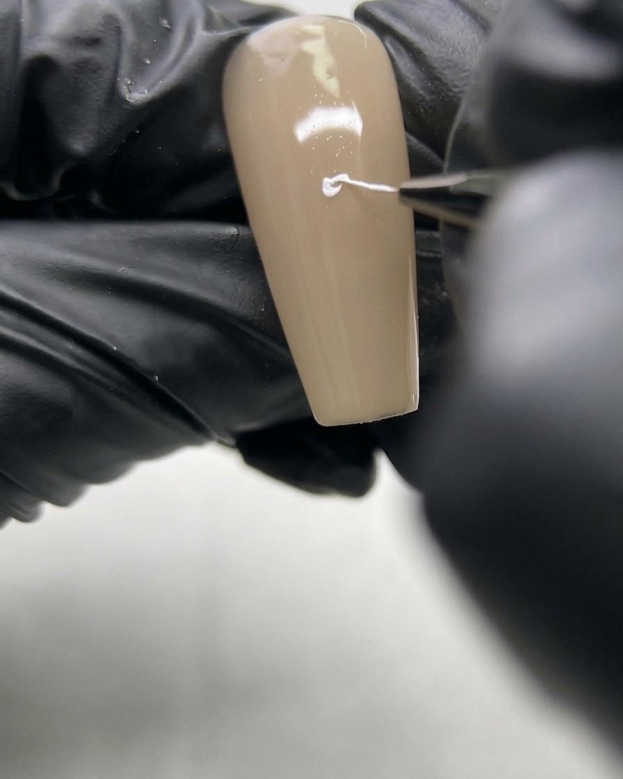 Un ongle avec un cœur blanc et deux lignes descendantes formant une forme en Y.