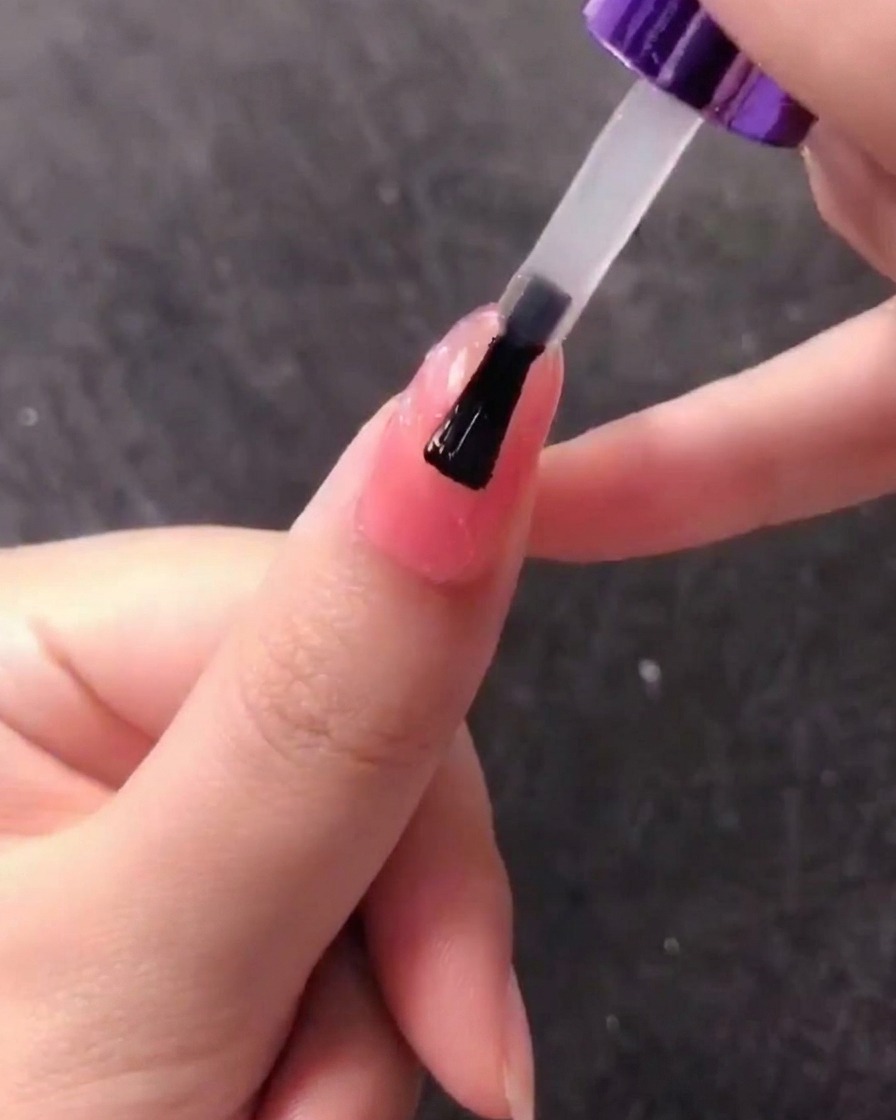 Un pinceau appliquant une couche de gel transparent sur le design dongle coquillage texturé.