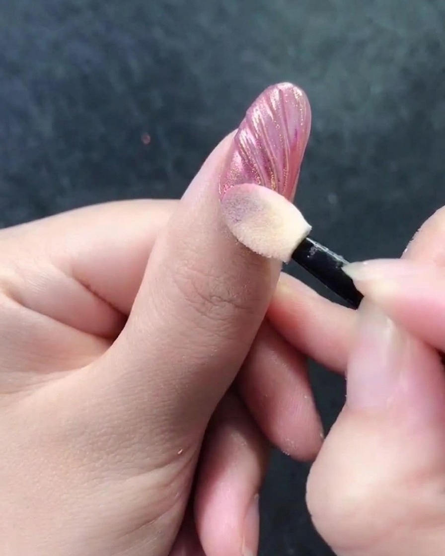 Un applicateur mousse polissant la poudre chromée dans les crêtes dun design dongle coquillage.