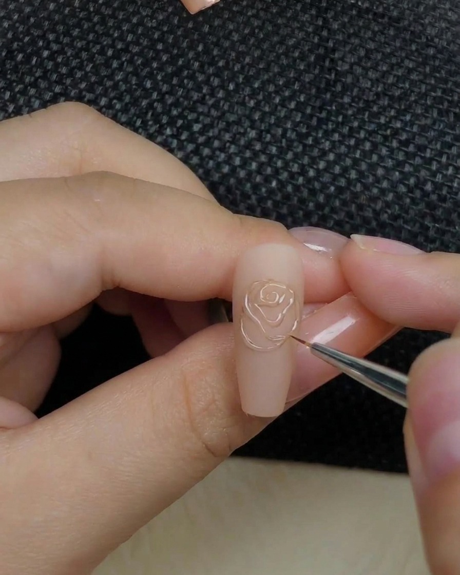 Gros plan dune main plaçant un ongle avec un motif de rose en relief dans une lampe de catalysation.
