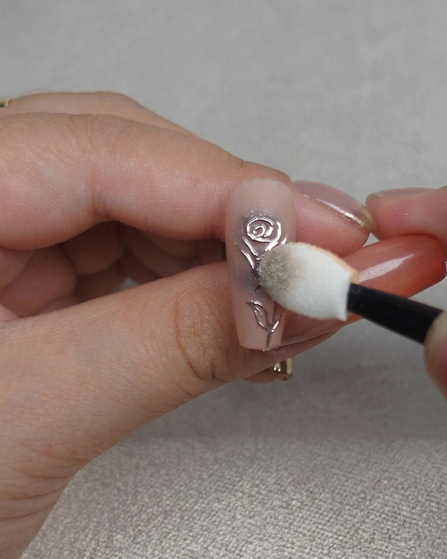 Gros plan dune éponge polissant de la poudre chrome dans les rainures dun design dongle rose 3D, créant un fini métallique très brillant.